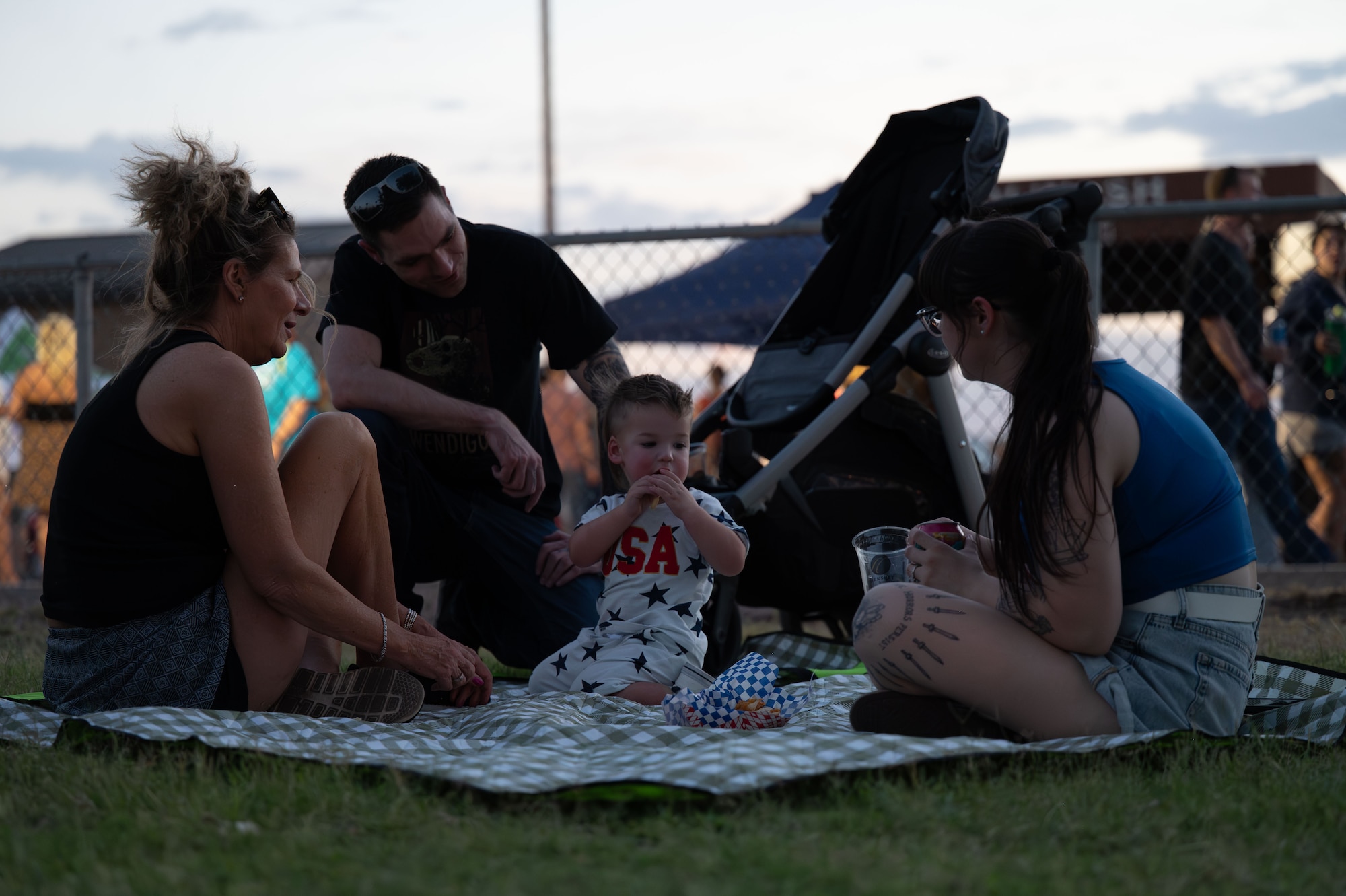 A Desert Lightning team family relaxes on the lawn during Freedom Fest at Davis-Monthan Air Force Base, Arizona, June 12, 2026. The annual event fostered camaraderie and unit cohesion by bringing together members of the Davis-Monthan community for an evening of live entertainment, food and family-friendly activities. (U.S. Air Force photo by Airman 1st Class Jaden Kidd)