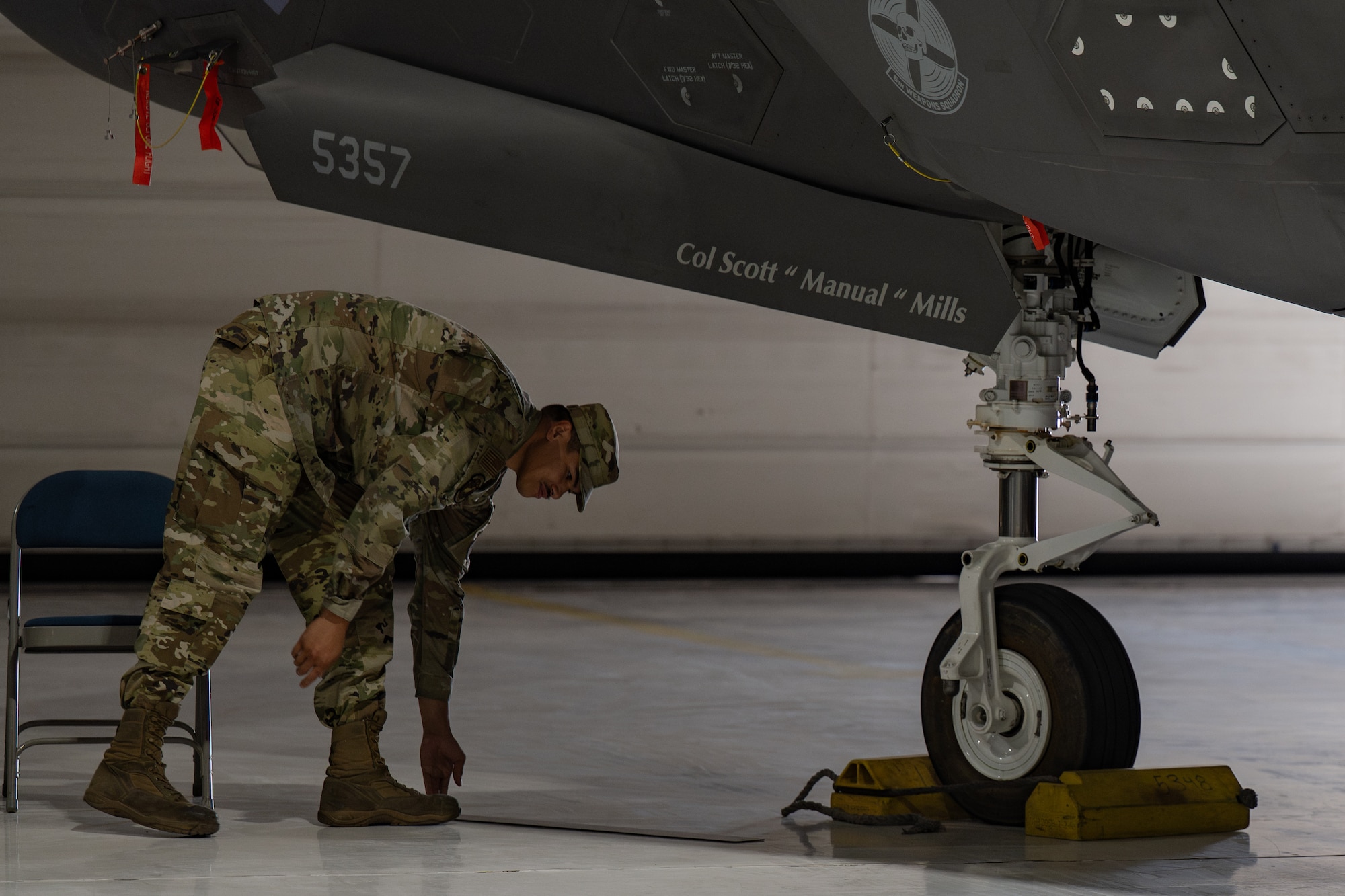 An Airman takes off a name tape from an F-35 Lightning II aircraft and places the magnet on the floor.