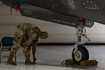 An Airman takes off a name tape from an F-35 Lightning II aircraft and places the magnet on the floor.