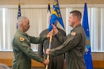 U.S. Air Force Brig. Gen. David Cochran, Assistant Adjutant General-Air, West Virginia National Guard, hands Col. Randall Wright the 167th Airlift Wing’s guidon during a change of command ceremony at the 167th Airlift Wing dining facility, Martinsburg, West Virginia, June 13, 2026. The guidon is a physical embodiment of the wing’s history, lineage, and the loyalty of the airman serving beneath it. (U.S. Air National Guard photo by Staff Sgt. Tim Sencindiver)