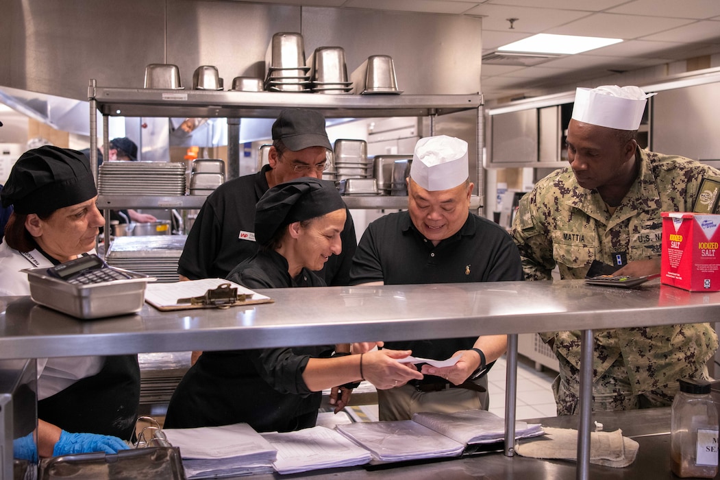 Minoan Taverna employees, assigned to Naval Support Activity (NSA) Souda Bay, Greece, discuss food preparation with Commander, Navy Region Europe, Africa, Central GL Food Service Specialist Francisco Marigundon in the Minoan Taverna during the 5-Star Galley Accreditation Inspection, June 4, 2026.