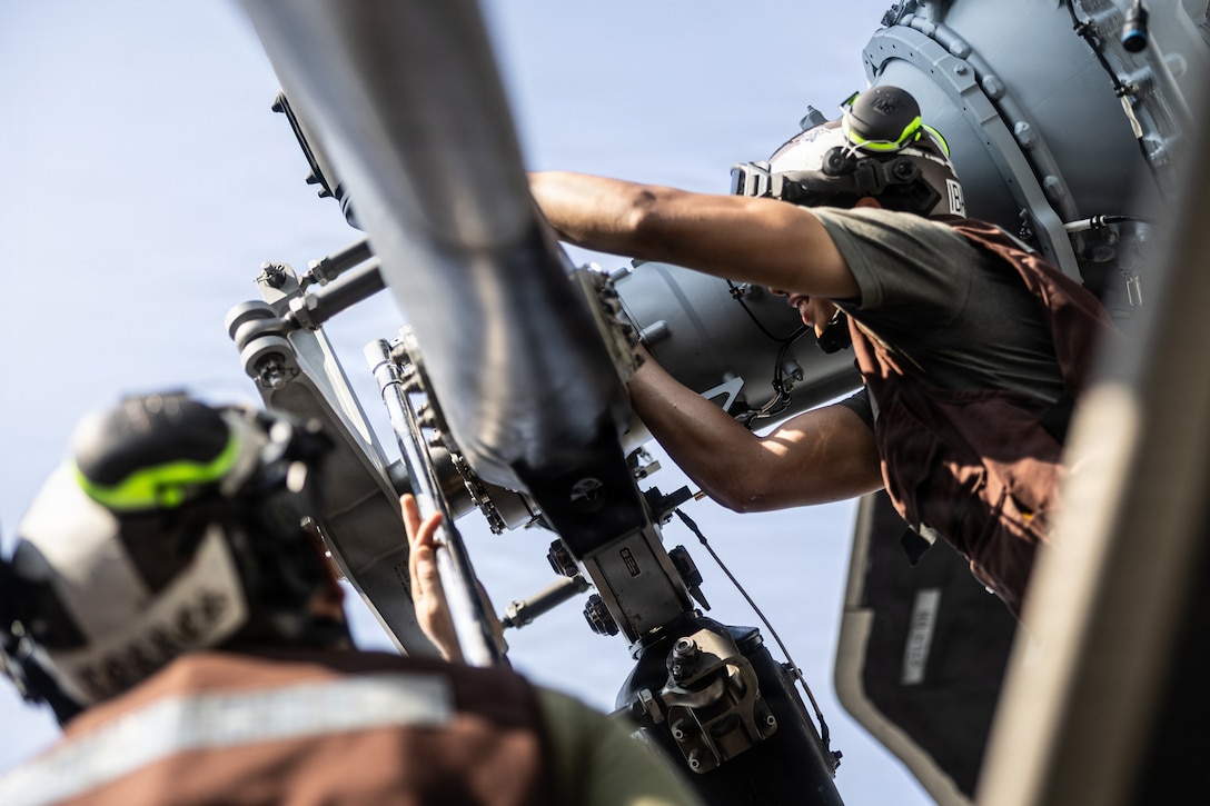 U.S. Marine Corps Cpl. Andres Ibarra, right, a California native, and Sgt. Grant Phillips, a North Carolina native, both crew chiefs with Marine Heavy Helicopter Squadron (HMH) 461, conduct maintenance on a CH-53K King Stallion during Type Commander’s Amphibious Training aboard San Antonio-class amphibious transport dock ship USS Arlington (LPD 24) June 14, 2026. TCAT is a military exercise designed to enhance mobility and integration between the U.S. Marine Corps and the U.S. Navy. The amphibious force is an integrated powerhouse providing sea, land, and air operations, giving geographic combatant commanders a more flexible, agile force for aggregated or dis-aggregated operations across the globe. (U.S. Marine Corps photo by Cpl. Osmar VasquezHernandez)
