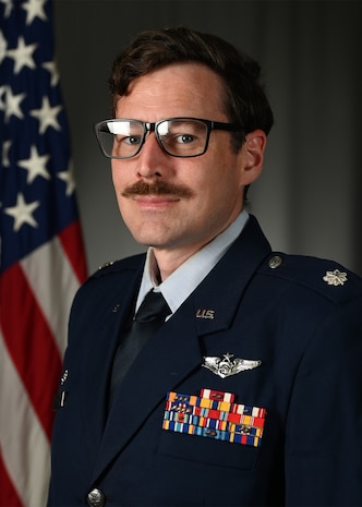 photo of US Air Force Airman standing in front of a US flag