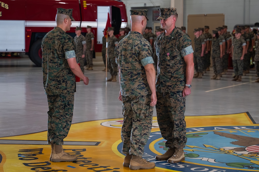 U.S. Marine Corps Col. James C. Ford III, Marine Aviation Training Support Group 22 commanding officer, presents Lt. Col. Brian Meade, outgoing Marine Corps Detachment Goodfellow commanding officer, with the Meritorious Service Medal during a change of command ceremony at the Louis F. Garland Department of War Fire Academy, Goodfellow Air Force Base, Texas, June 12, 2026. Meade was awarded the medal for leading and developing 2700 entry level signals intelligence and firefighter Marines, helping modernize the Basic Signals Operator course, removing academic barriers in the firefighter training pipeline and saving the Marine Corps over $3.4 million dollars annually. (U.S. Air Force photo by Senior Airman Brian Lummus)