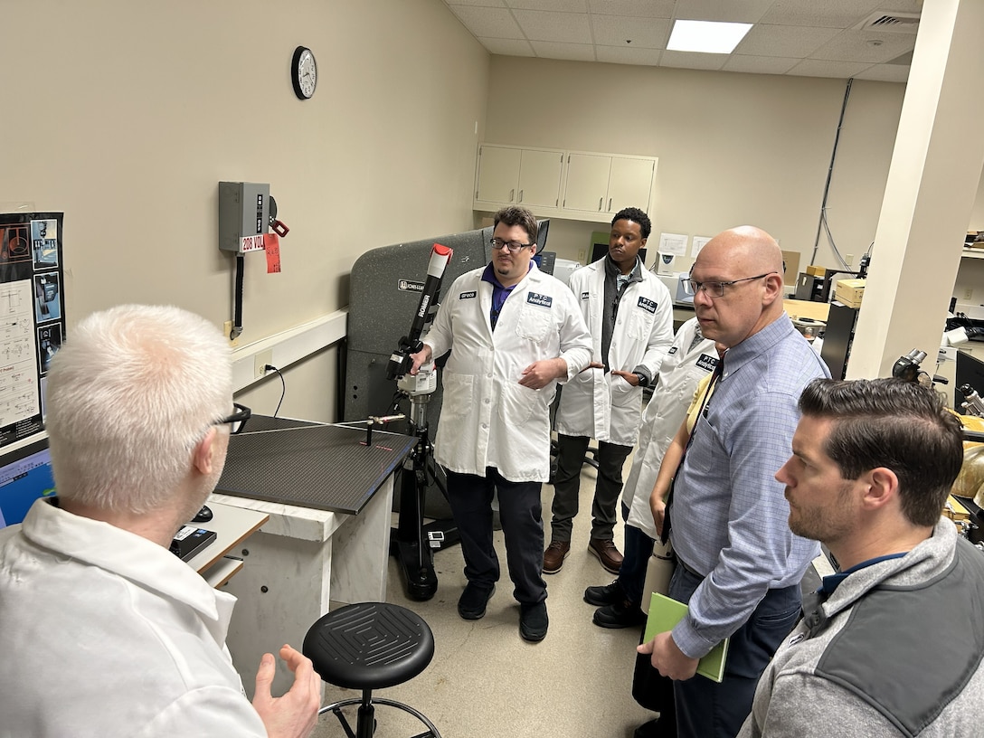 scientists and logisticians observe sword in testing equipment
