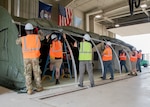 Military and DLA Civilian Members of the Contingency Overseas Readiness Exercise team construct an Alaska Small Shelter at their exercise site in Battle Creek, Michigan.