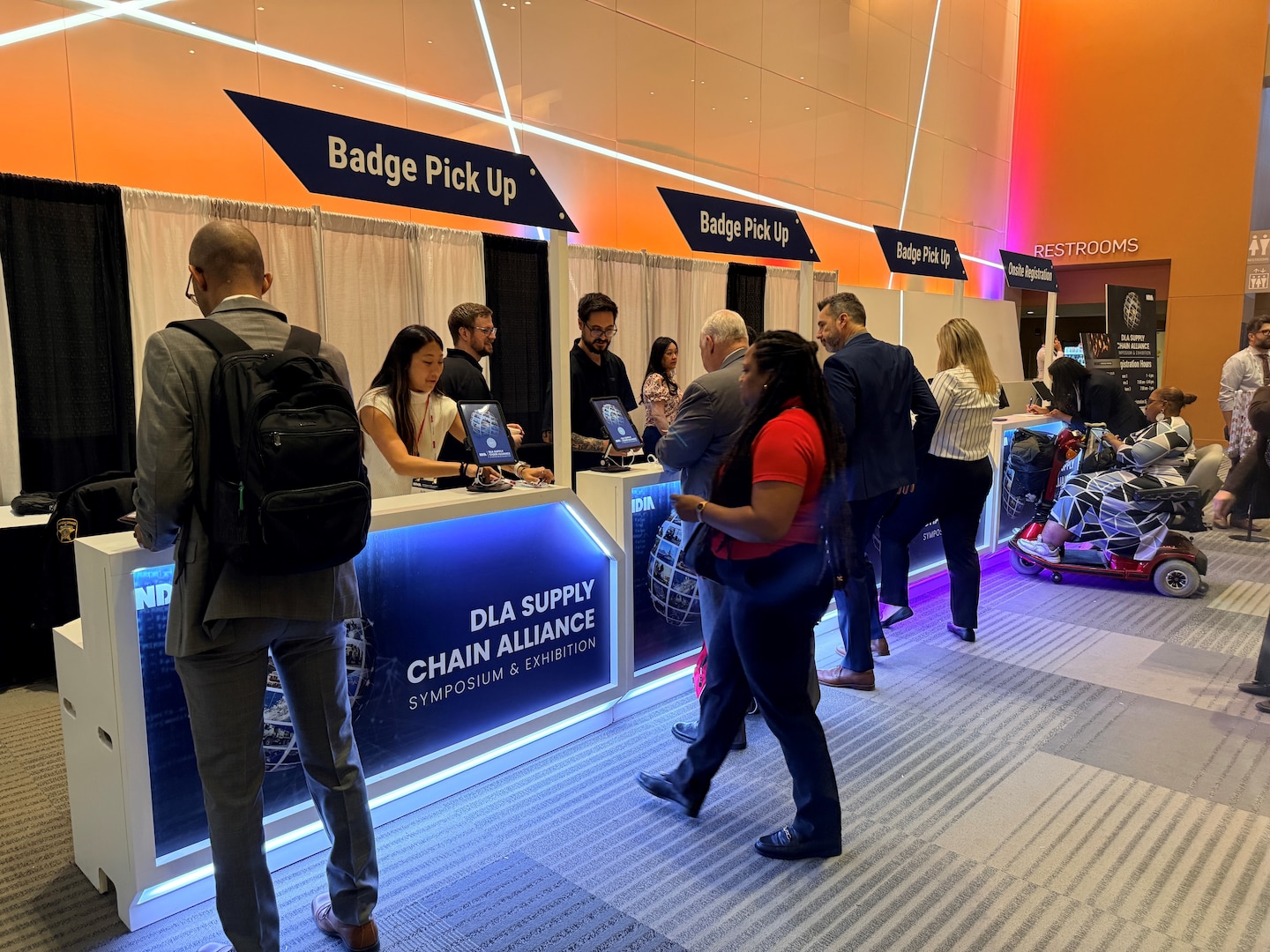People stand at a reception area to register for a conference.