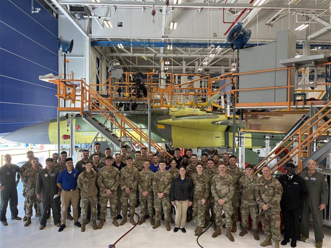 A group of military personnel stand in front of an aircraft