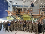 A group of military personnel stand in front of an aircraft