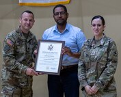 Lt. Col. Russell Hayes, 33rd Infantry Brigade Combat Team executive officer, presents a certificate of appreciation to Leosvaldo Rosa, the husband of Chief Warrant Officer 3 Jennifer Rosa, in honor of his support of his spouse during her military service during a retirement ceremony June 5 at the brigade headquarters in Urbana.
