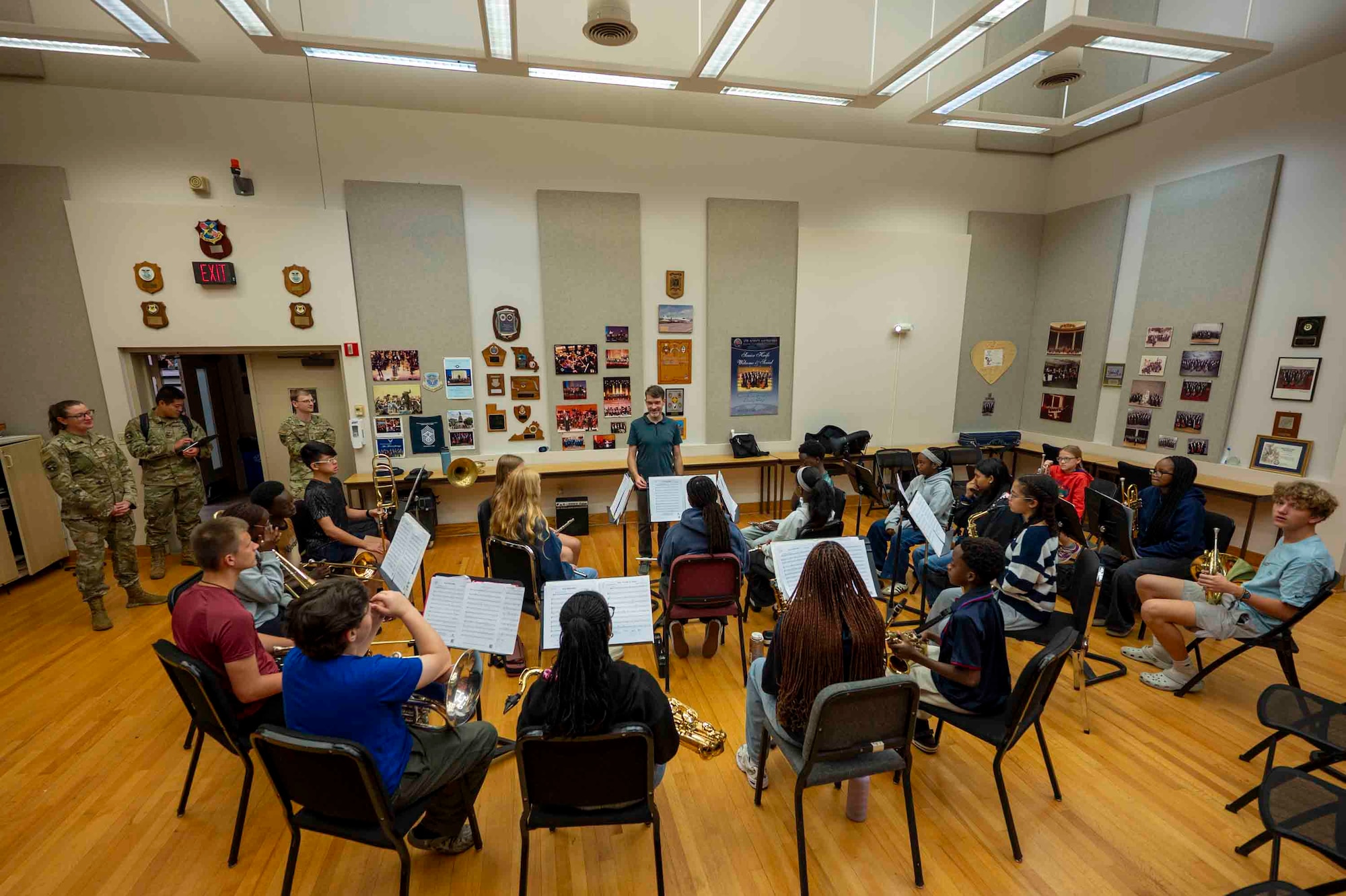 A student wind ensemble sits in a semicircle around the conductor.