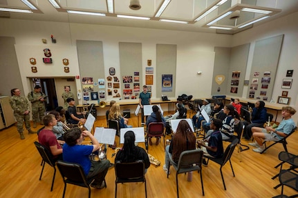 A student wind ensemble sits in a semicircle around the conductor.