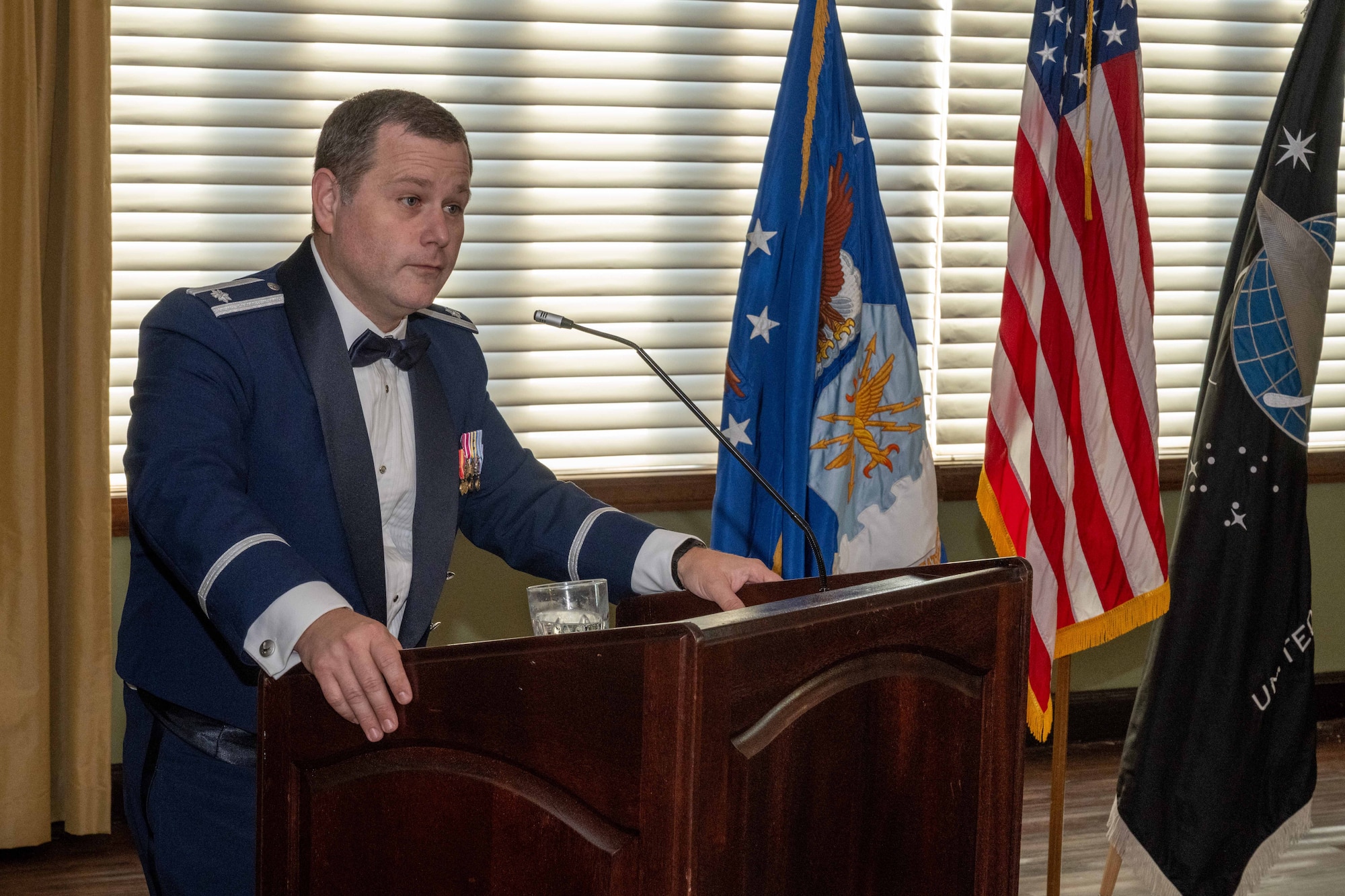 A man stands at a podium giving a speech. He's dressed in his blue mess dress uniform.