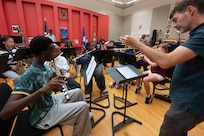 A man conducts students playing wind instruments.