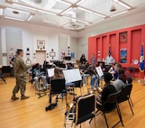 An Airman stands in front of students playing instruments.