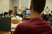 A student films the band with a phone.
