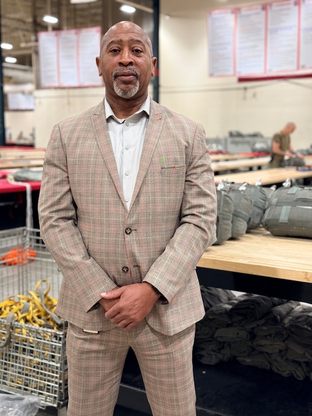 A man wearing a tan suit poses for a photo.