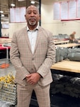 A man wearing a tan suit poses for a photo.