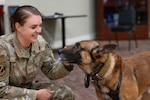 U.S. Air Force Staff Sgt. Maddison L. Miller, 802d Security Forces Squadron military working dog handler, smiles at Military Working Dog CCoolahan during CCoolahan's retirement ceremony at Joint Base San Antonio-Lackland, Texas, June 5, 2026. The ceremony recognized CCoolahan's service to the U.S. Air Force and the 802d Security Forces Squadron. (U.S. Air Force photo by Marcus Robins)
