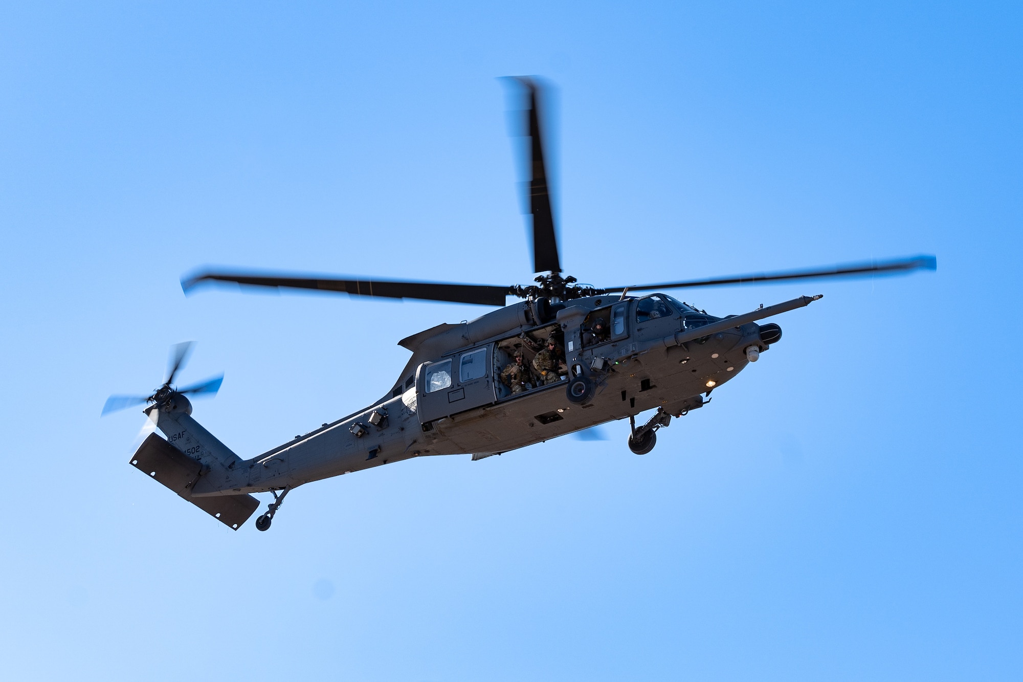 A HH-60W Jolly Green II performs a fast rope infiltration demonstration in the air.