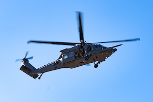A HH-60W Jolly Green II performs a fast rope infiltration demonstration in the air.