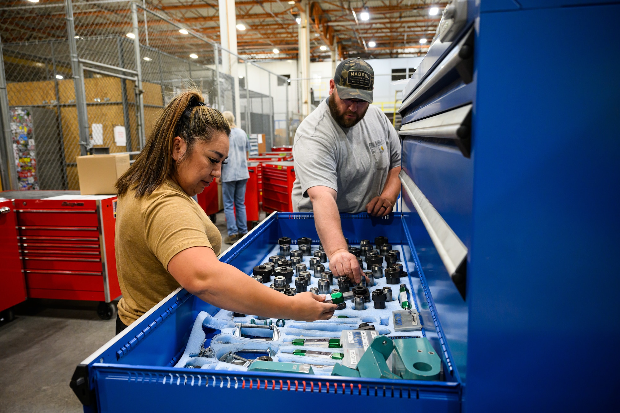 Toni Beausoleil and Jeff Dalling reach together into an open drawer of a tool bin to retrieve items for a tool kit.