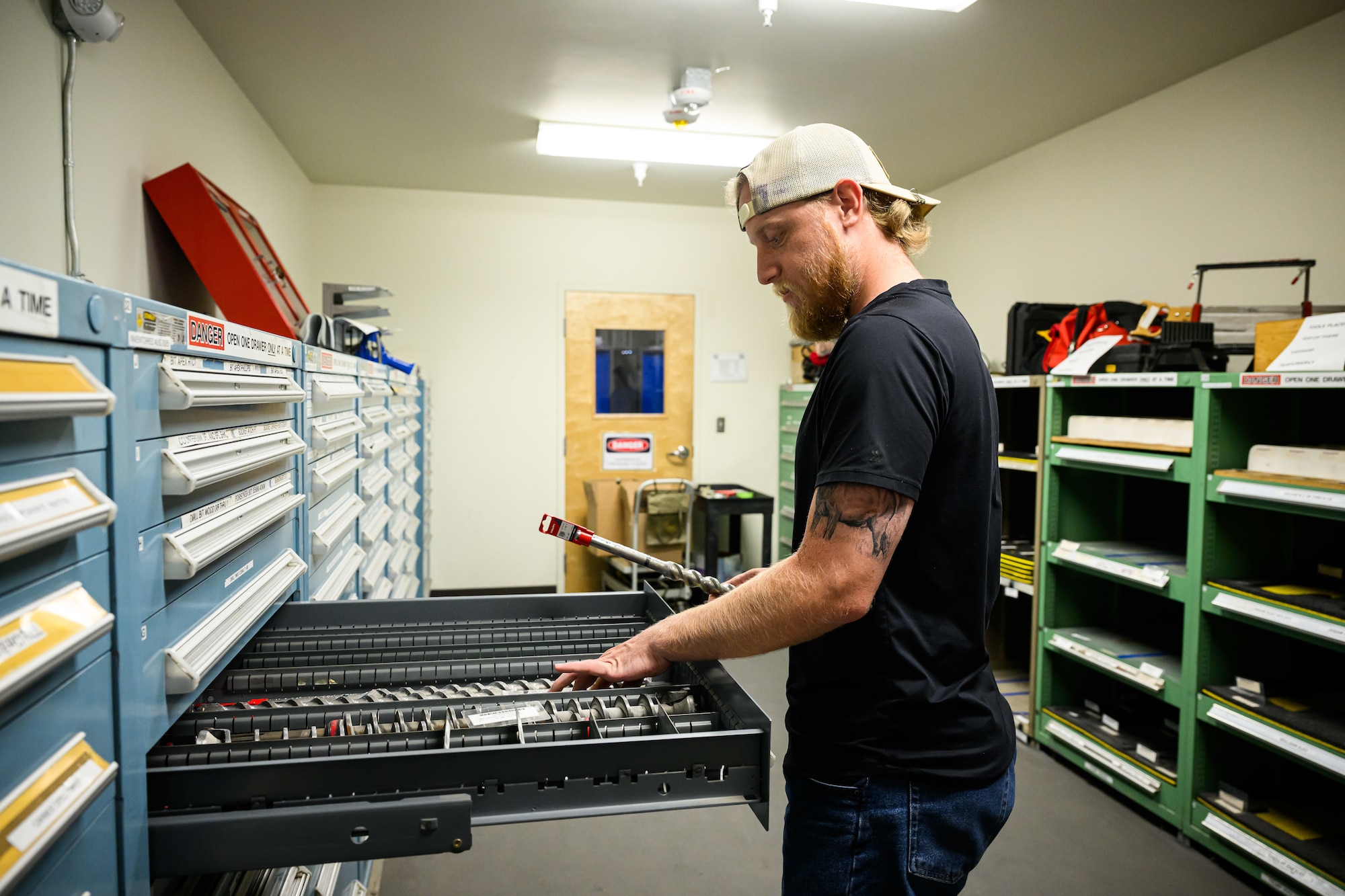 Jeremy Hale reaches into an open drawer of an industrial tool crib to retrieve a tool.