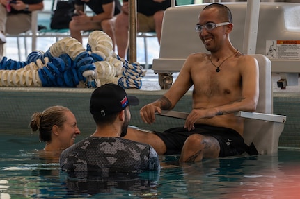Retired U.S. Army Spc. Jeyson Ruiz, speaks with Krystal Morris, Army Recovery Care Program Adaptive Reconditioning Action Officer, and  Eli English, Fort Benning Adaptive Reconditioning Lead, during swimming training for the 2026 Warrior Games in San Antonio, Texas, June 11, 2026.