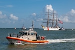 A Coast Guard Station Galveston 45-foot Response Boat-Medium provides security as the U.S. Coast Guard Cutter Barque Eagle transits the Galveston Channel towards Pier 21 in Galveston, Texas, June 10, 2022. Homeported at the Coast Guard Academy in New London, Conn., the Eagle is used as a training platform for future Coast Guard officers and visited Galveston, Texas, for the first time since 1972. (U.S. Coast Guard photo by Petty Officer 2nd Class Ryan Dickinson)
