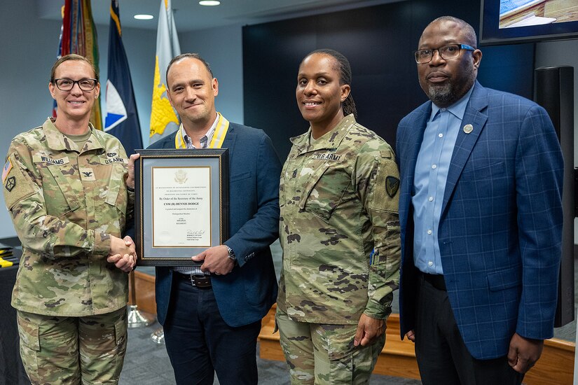 Retired Command Sgt. Maj. Dennis Dodge, U.S. Army Financial Management Command senior quality assurance analyst, receives a U.S. Army Finance Corps Distinguished Member of the Regiment award from Col. Michelle M. Williams, USAFMCOM commander, left; Command Sgt. Maj. Joy L. Allen, USAFMCOM senior enlisted advisor, center right; and retired Command Sgt. Maj. Gennaro Penn, Finance Corps Association president at the Maj. Gen. Emmett J. Bean Federal Center in Indianapolis June 15, 2026. The Finance Corps designated the first DMR on May 5, 1990, and the program honors individuals whose legacy of landmark contributions and unique acts brings significant credit to the Finance Corps. (U.S. Army photo by Mark R. W. Orders-Woempner)