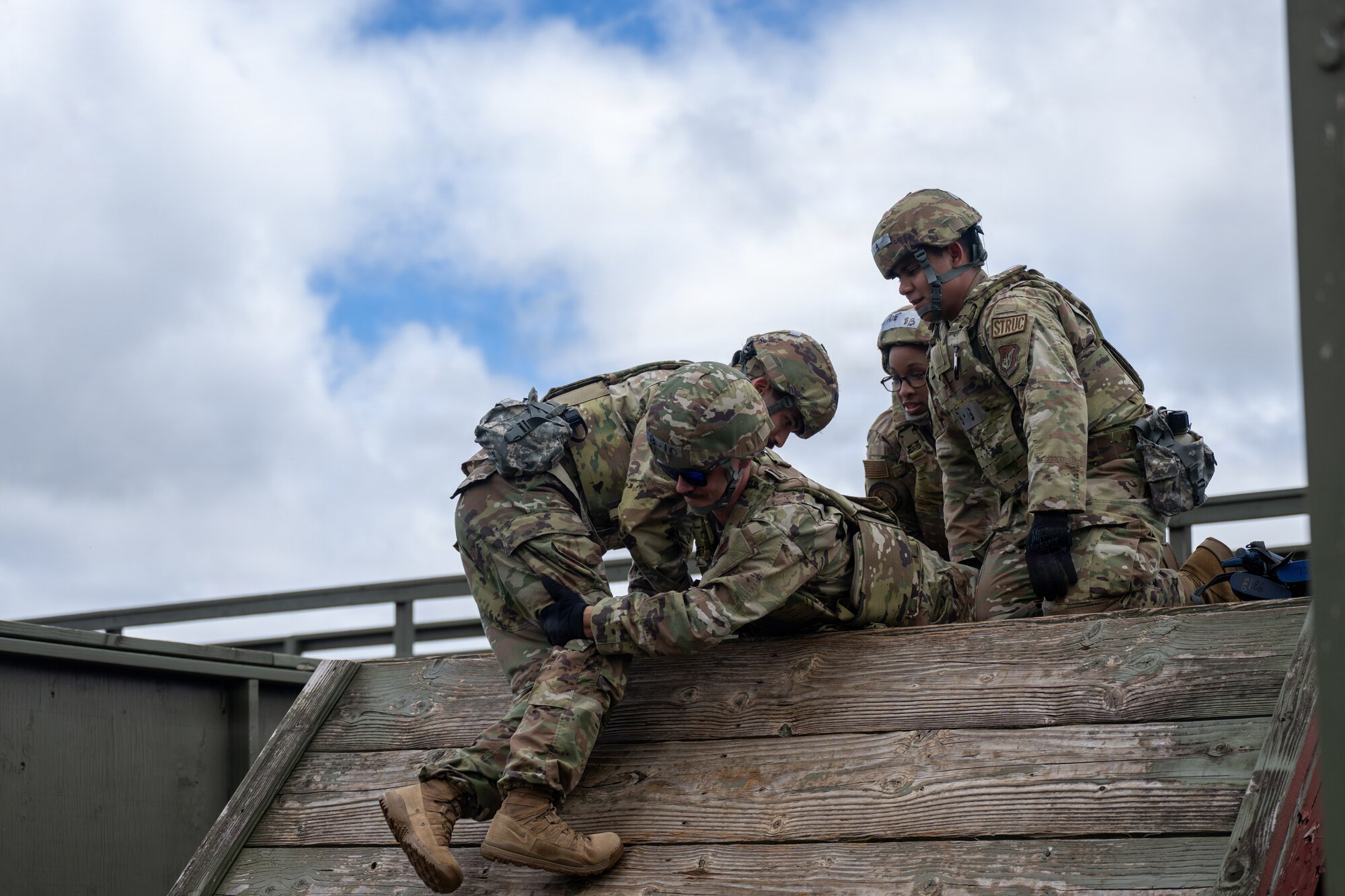 U.S. Air Force Airmen help each other climb an obstacle on the Leadership Reaction Course during Vanguard Expeditionary Training 02-26.