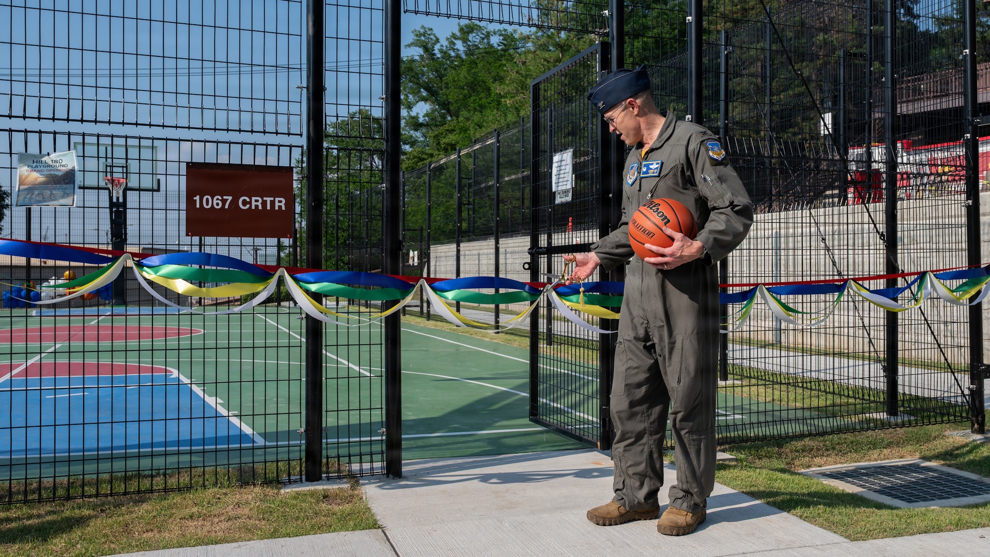 Man cuts ribbon during playground grand opening ceremony.