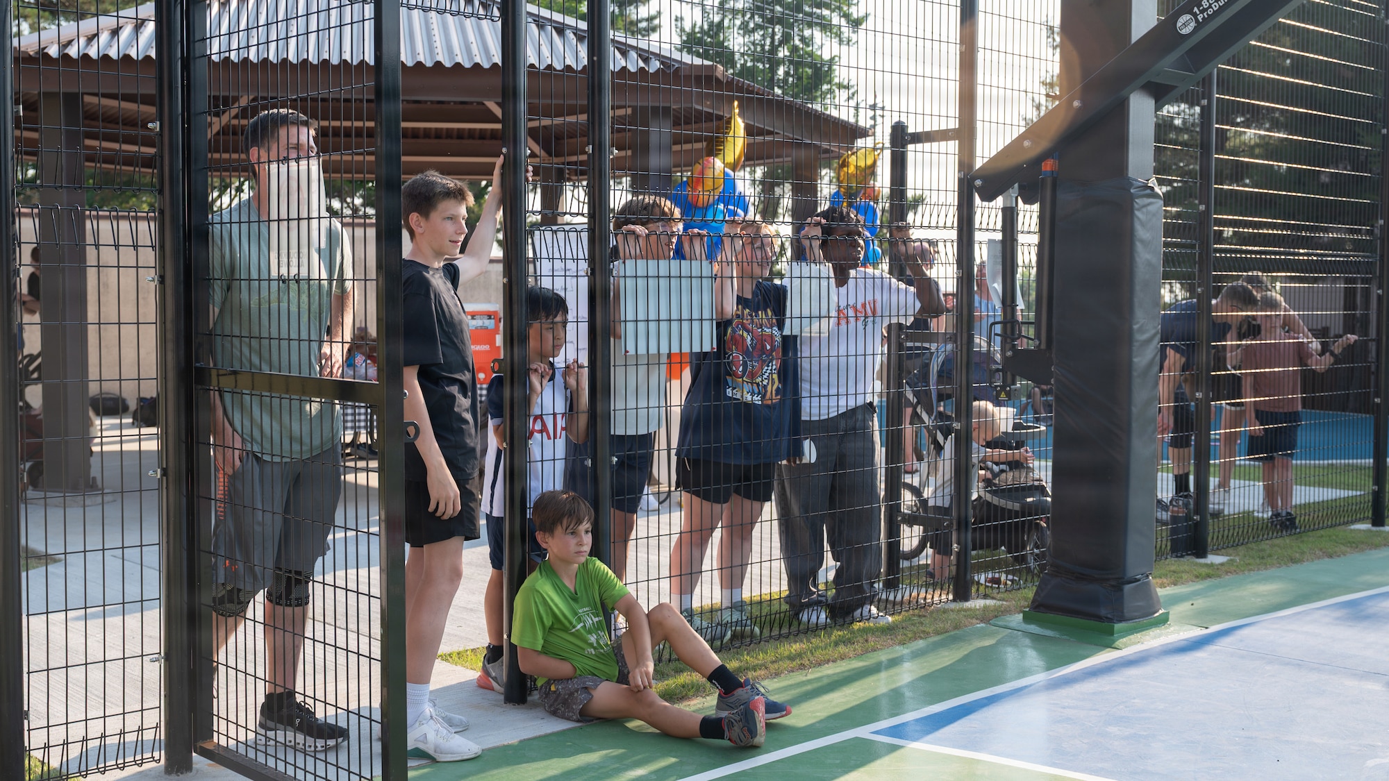 People watching a basketball match from outside the court.