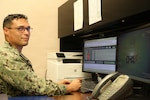 Hospital Corpsman 1st Class Jordan Cooper at his desk in Staff Education and Training, demonstrates the DHMHRSi Excel calculator tool at Naval Health Clinic Lemoore. (Department of War photo by Elaine Heirigs/Released)