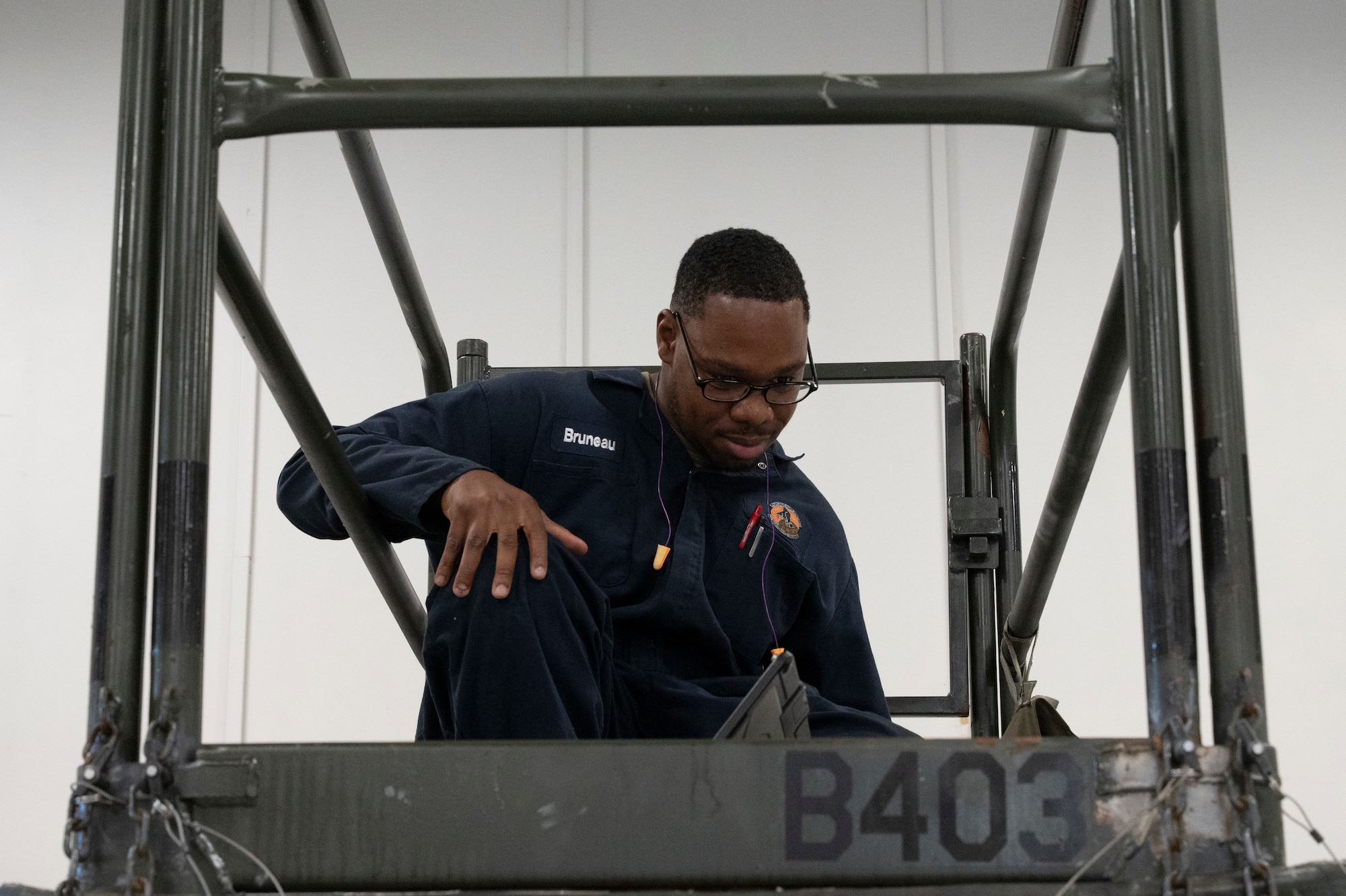 A man crouching on a platform staring at a tablet.