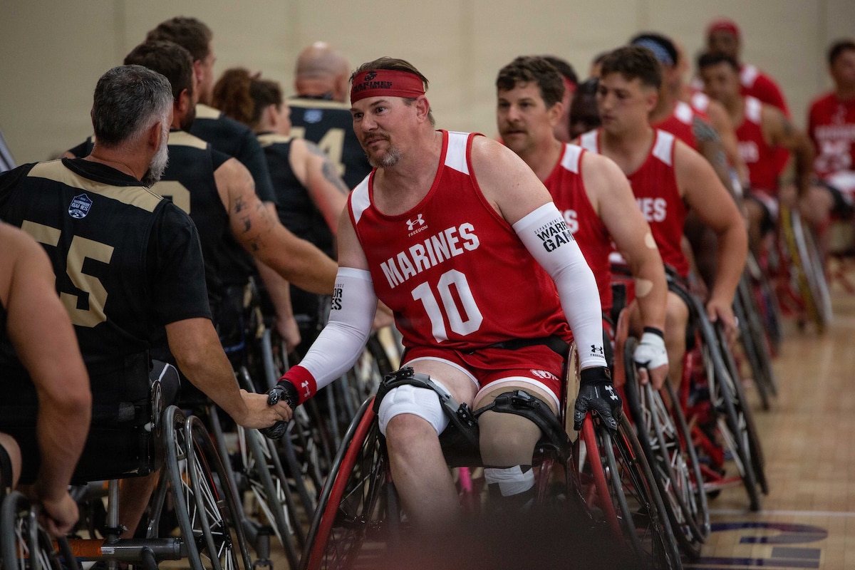 Blue graphic with white lettering reading "WARRIOR GAMES" and a logo.