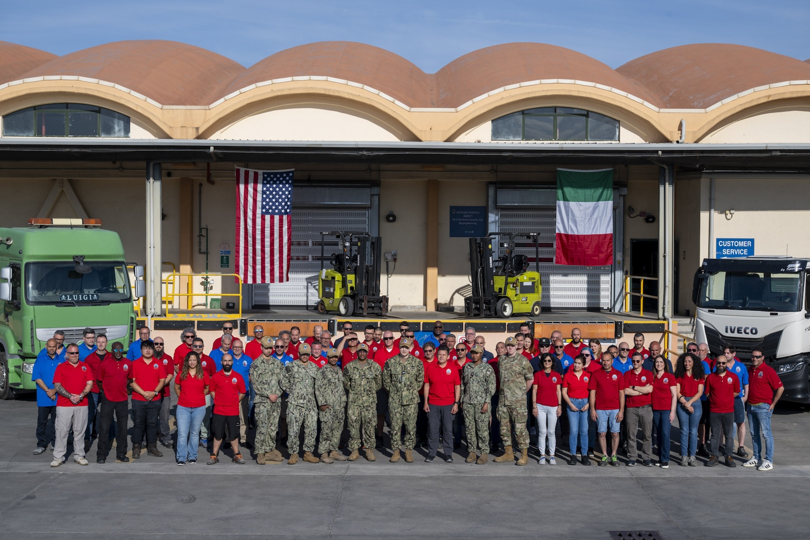 A group of people stand outside of a warehouse.