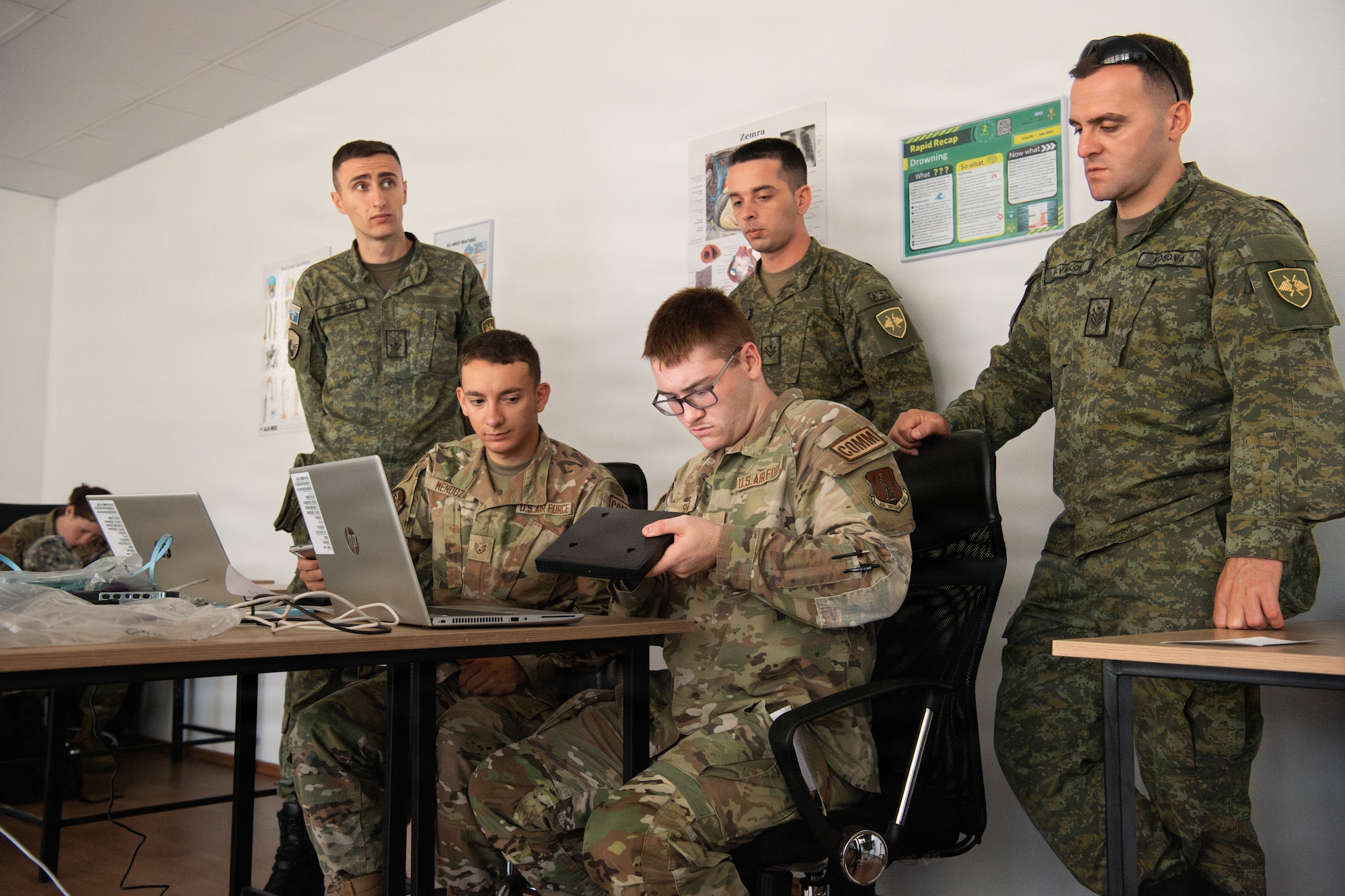 A group of U.S. Air National Guard airmen and KSF members look over computer screens in a building
