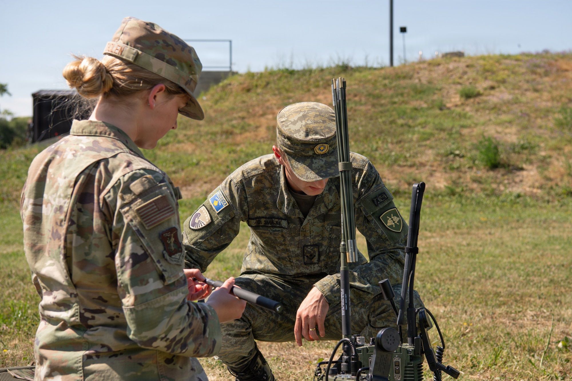 A US Airman and KSF member look at a radio outside.