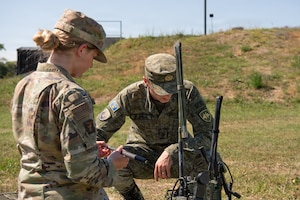 A US Airman and KSF member look at a radio outside.