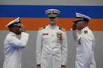 The incoming and outgoing Coast Guard commanding officers salute each other in front of the ceremony’s presiding officer.