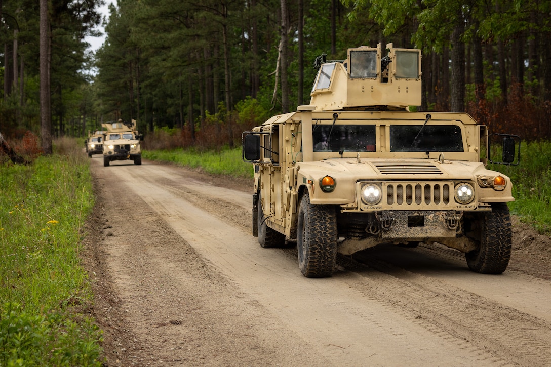 A Humvee drives down a dirt road.