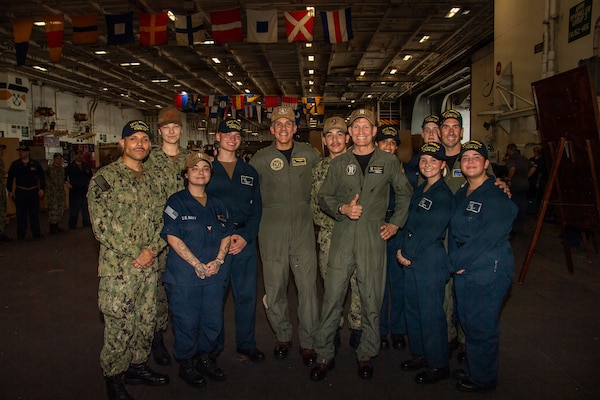 Rear Adm. Carlos Sardiello, commander of U.S. Naval Forces Southern Command/ U.S. 4th Fleet, and Rear Adm. Cassidy Norman, commander of Carrier Strike Group 11, pose for a photo with Sailors inside the hangar bay aboard Nimitz-class aircraft carrier USS Nimitz (CVN 68) while Nimitz is pierside in Naval Station Mayport in Jacksonville, Florida, June 16, 2026. Nimitz is underway in the U.S. 2nd Fleet Area of Operations as part of a scheduled homeport shift to Norfolk, Virginia. (U.S. Navy Photo by Mass Communication Specialist Seaman Apprentice Molly Guy)