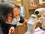 A dental assistant places a film in a patient's mouth in preparation for an X-ray.