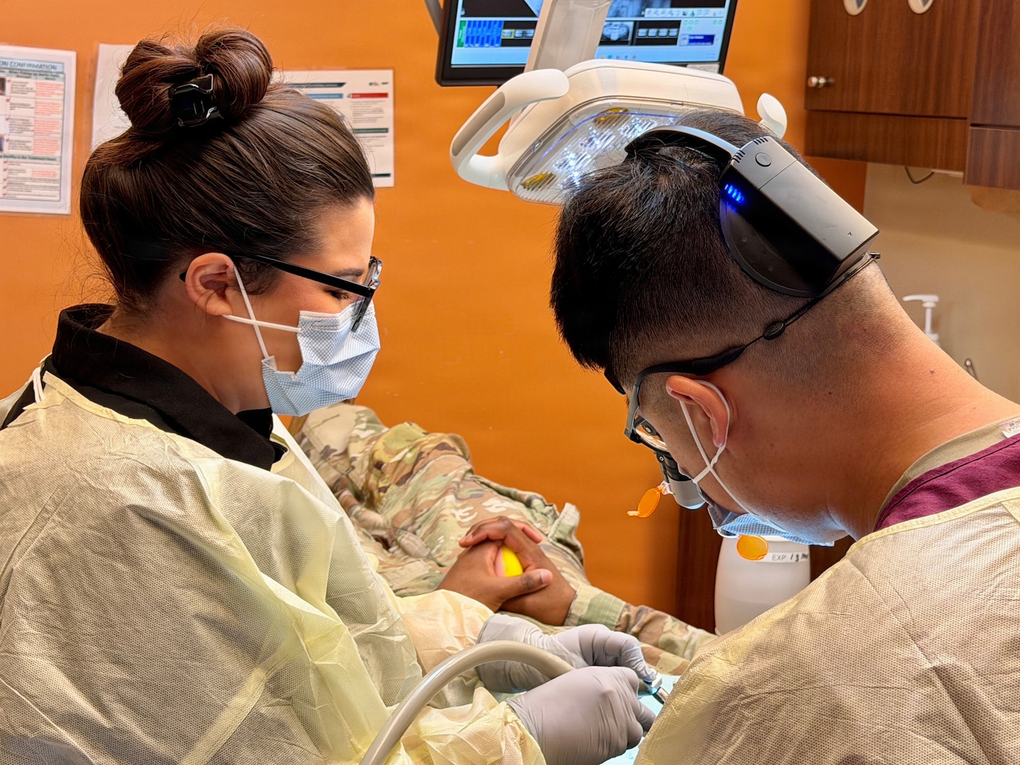 A Dental Assistant Program Graduate assists a dentist performing a procedure on a patient.