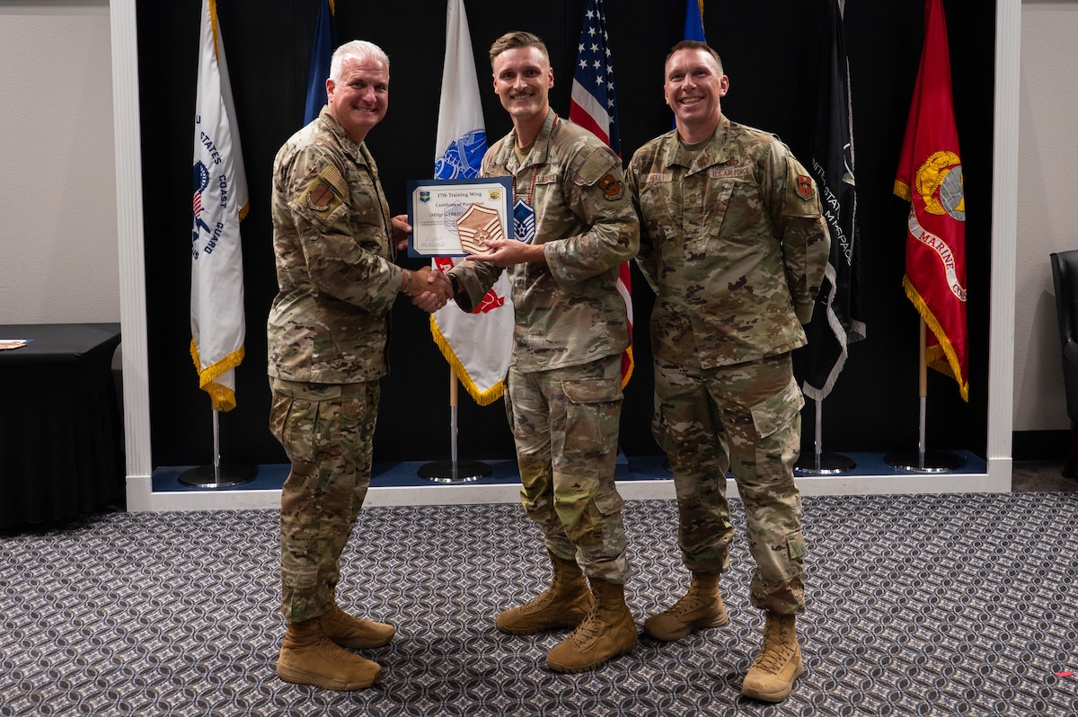 U.S. Air Force Tech. Sgt. Gabriel Shaffner, 17th Training Wing master sergeant select, poses for a photo with Col. Matthew Norton, 17th TRW commander, Chief Master Sgt. Derek Neill, 17th TRW command chief, during a master sergeant release party at the Powell Event Center, Goodfellow Air Force Base, Texas, June 16, 2026. Master sergeants transition from working as technical experts and frontline supervisors to dedicated administration roles while growing their technical and managerial talents. (U.S. Air Force photo by Senior Airman Brian Lummus)
