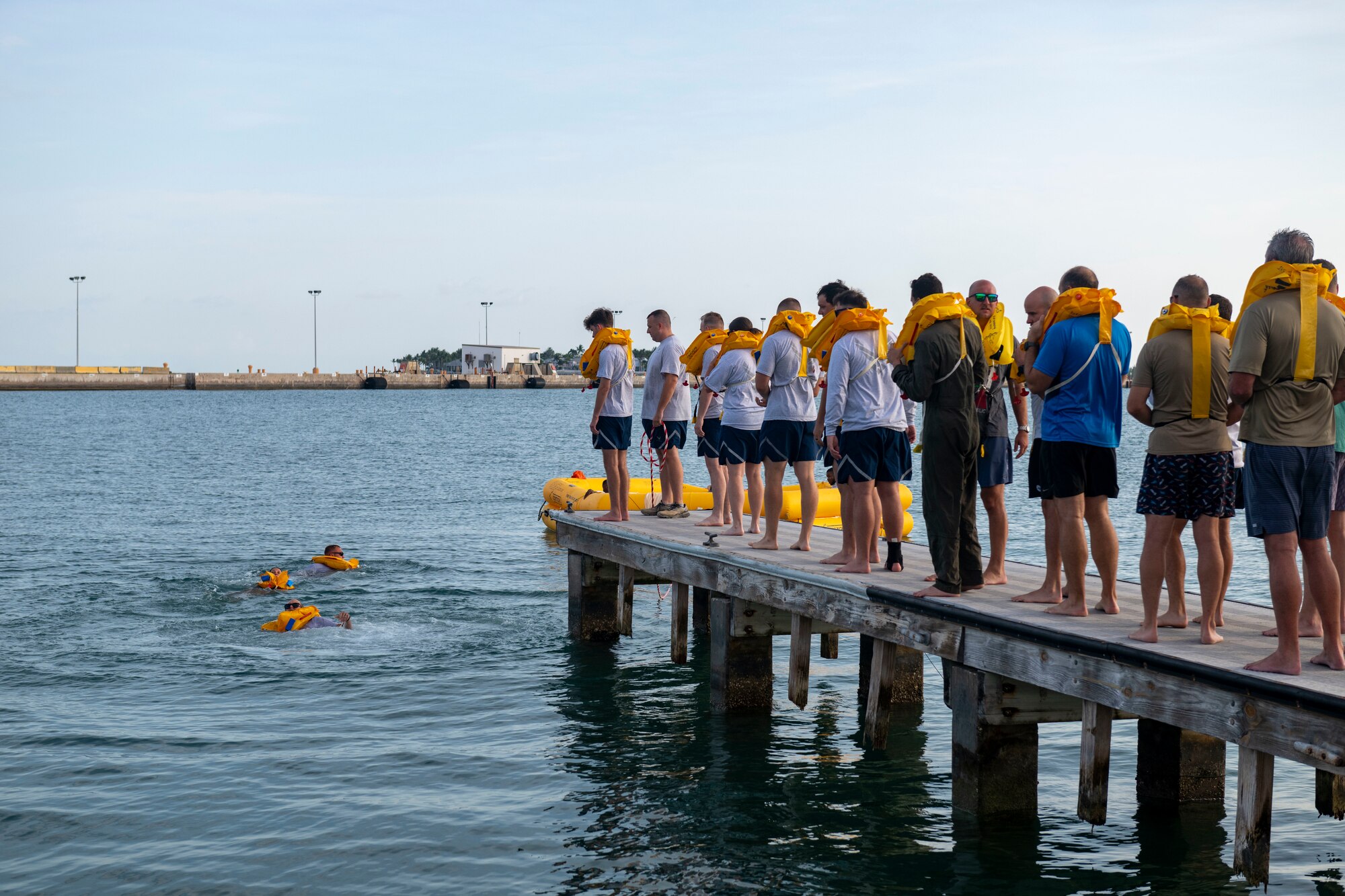U.S. Airmen assigned to the 183rd Airlift Squadron line up on the edge of the deck in preparation to jump into the water during Aircrew Flight Equipment (AFE) Water Survival Training in Key West, Florida, June 2, 2025. This training is designed to build confidence in open water and teach essential survival techniques in case of overwater aircraft emergencies.  (U.S. Air National Guard photo by Senior Airman Damara Burrell)