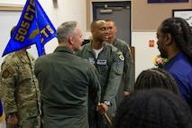 photo of USAF Airmen holding a unit flag in between them