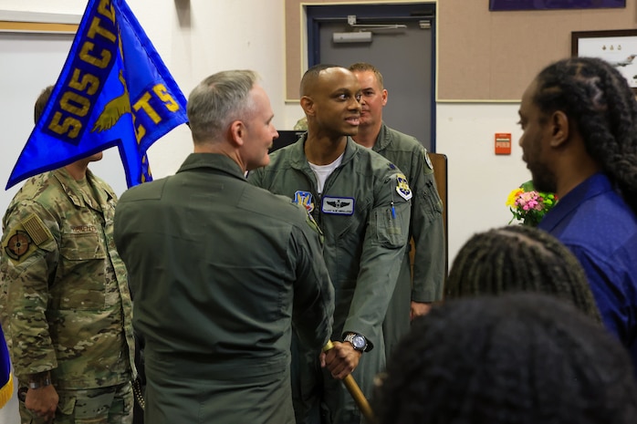 photo of USAF Airmen holding a unit flag in between them