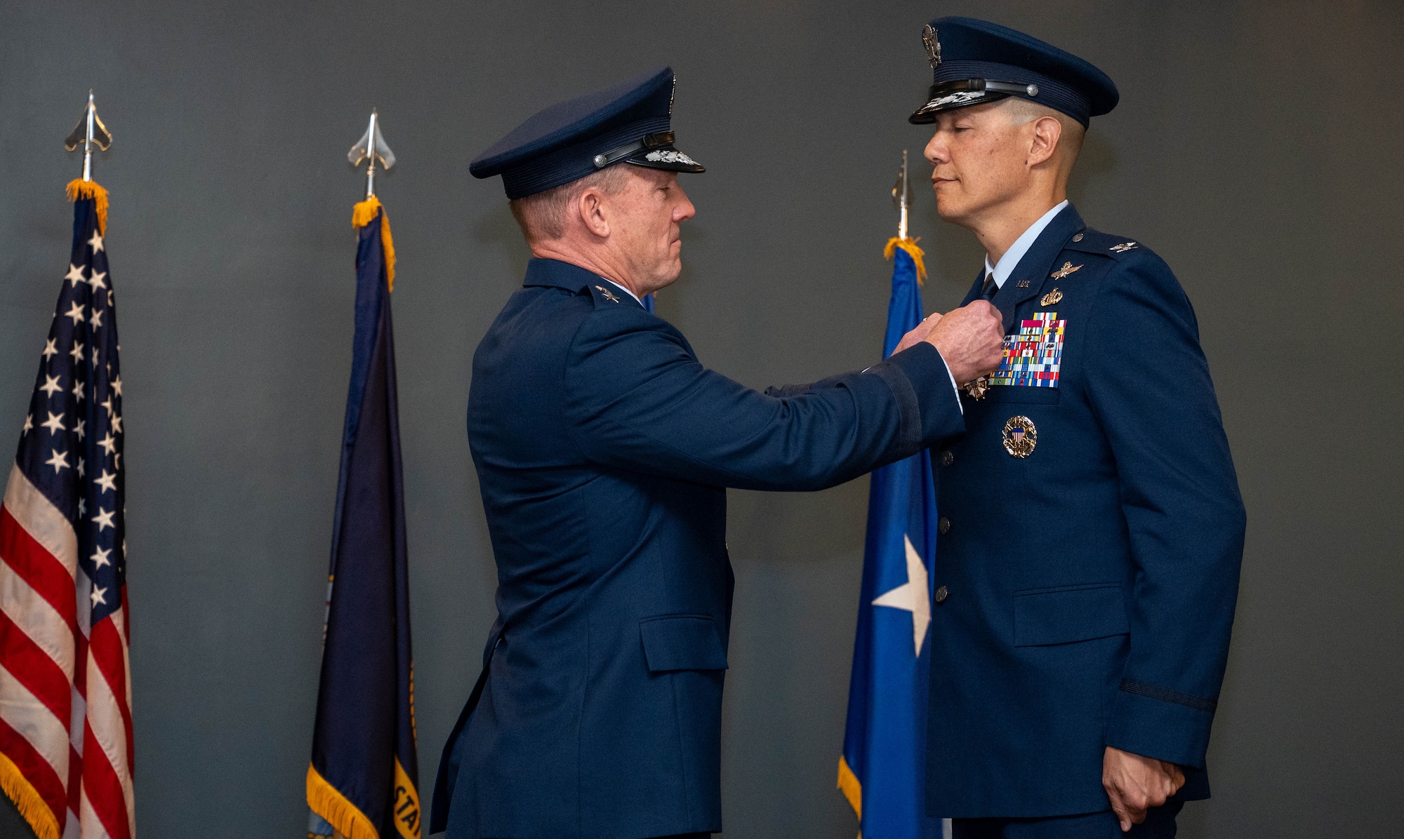 A man in uniform pins a medal to the lapel of another man in uniform.